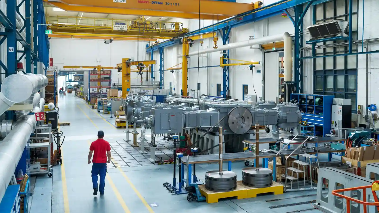 Compressor assembly hall with industrial machinery and overhead cranes.