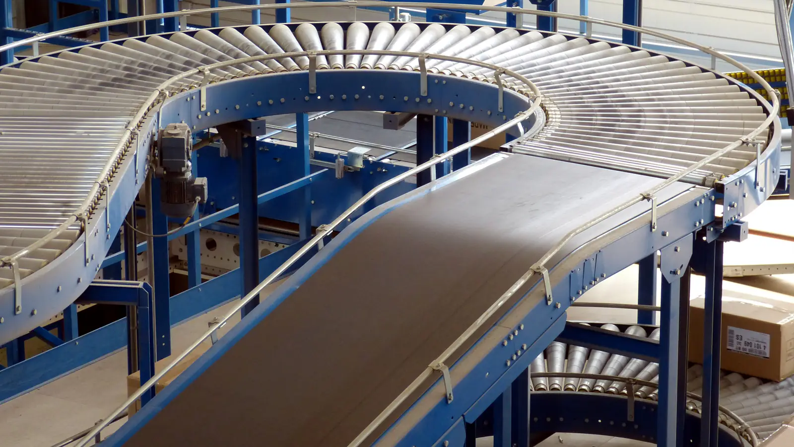 Curved roller and belt conveyors on a steel frame in a factory.