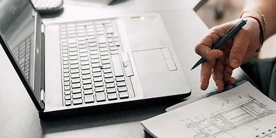 Laptop and technical drawing on an engineering worktable
