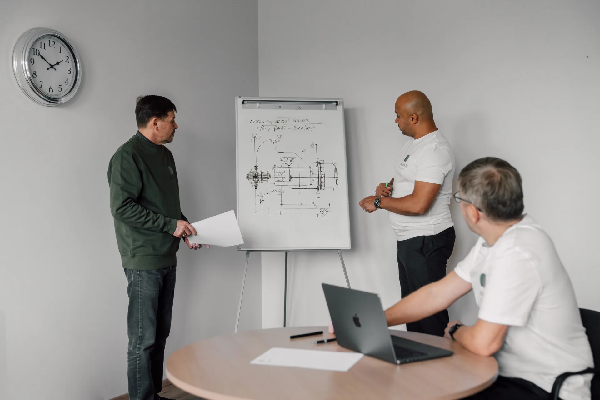 Engineers discuss technical drawings in the office.