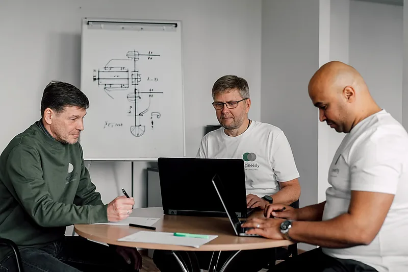 Engineers working together around a table with laptops.